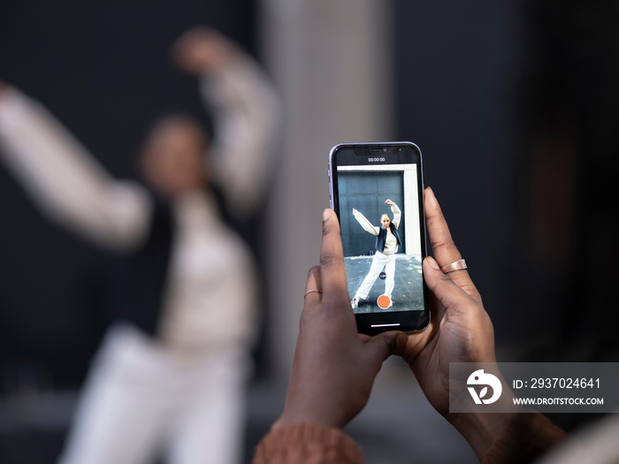 Close-up of woman photographing friend dancing in city