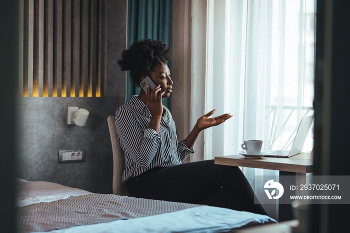 Outraged attractive employee talking on the phone, arguing with a client or customer, actively gestu