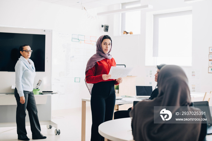 Confident teenage girl giving presentation in classroom at university