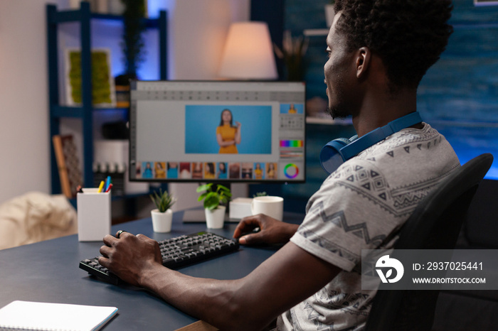 非裔美国摄影师坐在cr办公桌旁，使用图片修饰软件编辑图像
