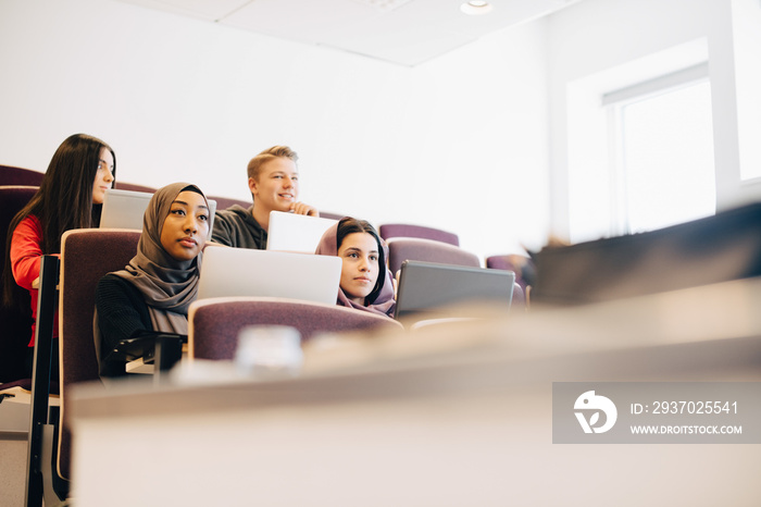 Low angle view of multi-ethnic students using laptops at desk in classroom