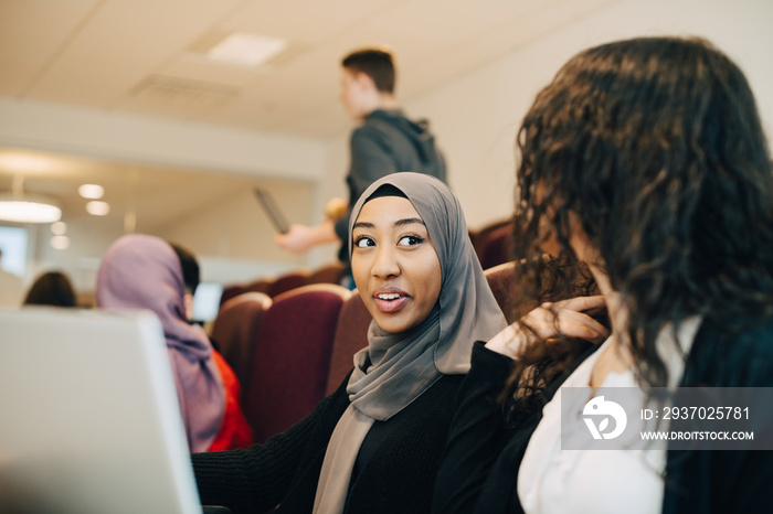 Multi-ethnic female friends talking during lectures in classroom