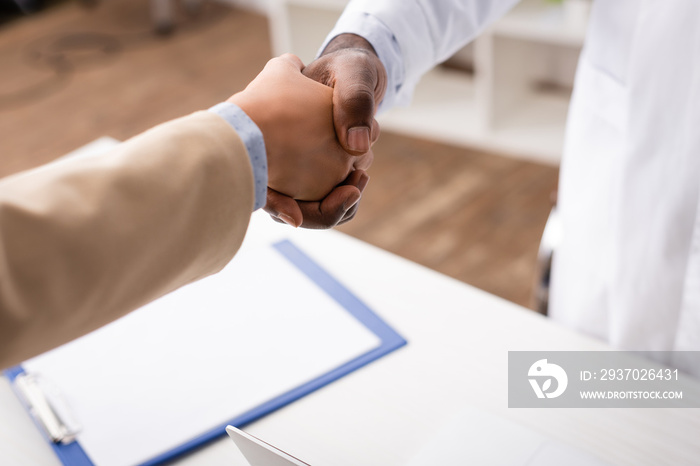 Selective focus of african american doctor shaking hands with patient