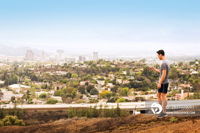 Man listening to music while doing sports outside city