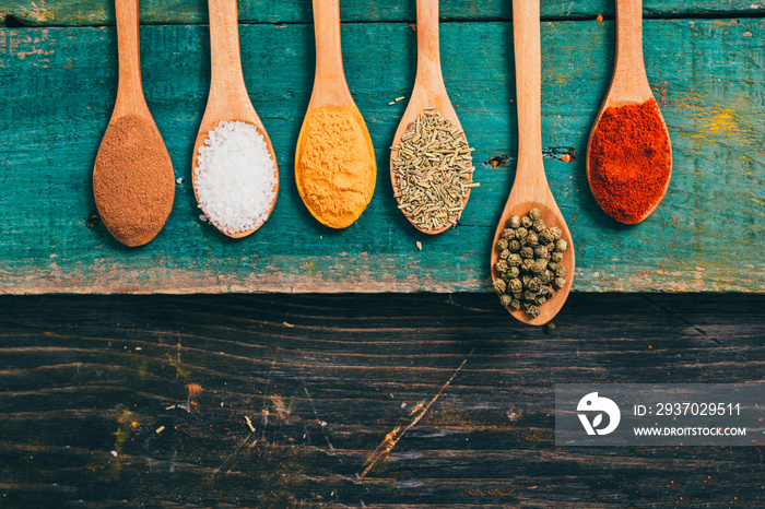 colorful spices in wooden spoons on table