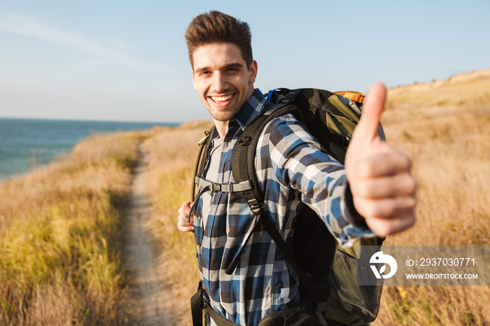 Attractive smiling young man carrying backpack