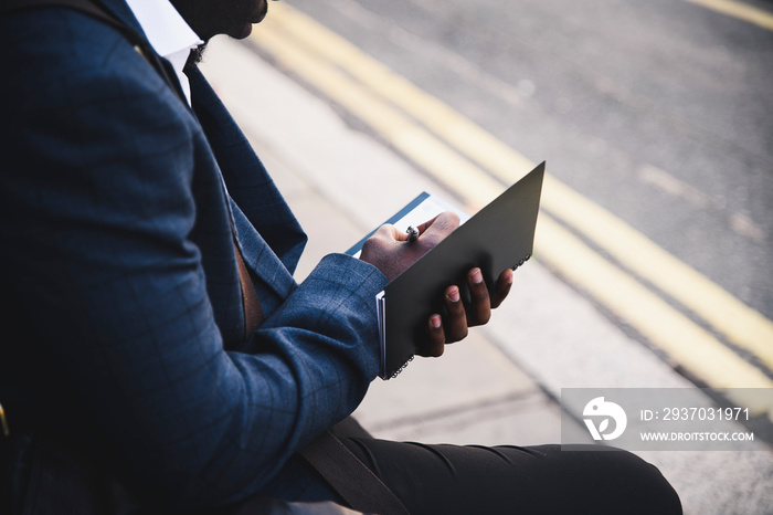 Businessman writing in a black notebook