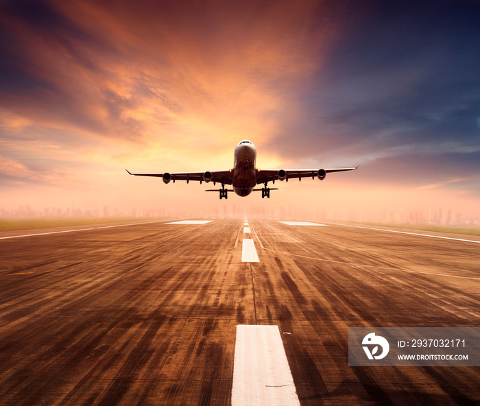 air plane flying over airport runway with city scape and sunset sky background