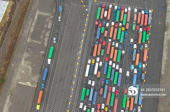 AERIAL: A large group of freight trucks line up before leaving the harbor.