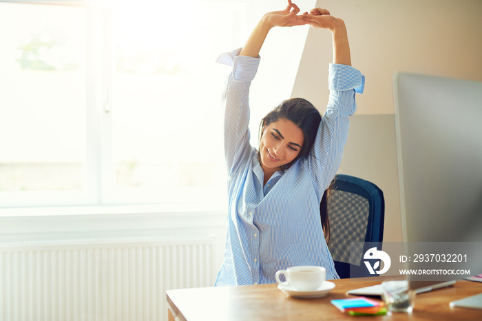 Woman stretching in front of desk at home