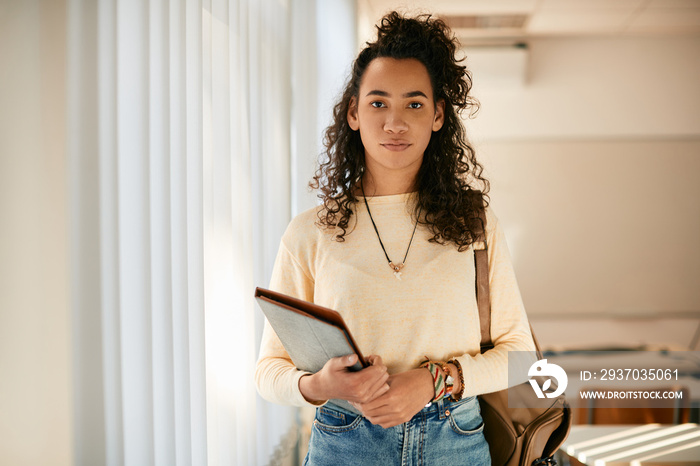 Portrait of black female high school student in classroom looks at camera.