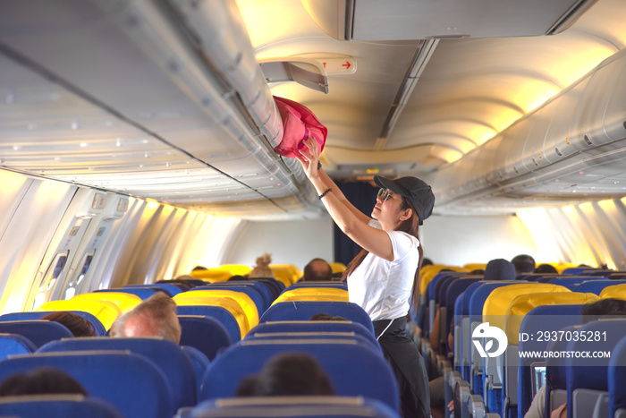 woman passenger traveler on boarding aircraft looking for empty overhead locker for luggage keep in 