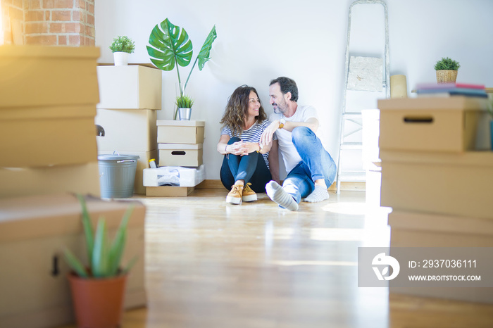 Middle age senior romantic couple in love sitting on the apartment floor with cardboard boxes around