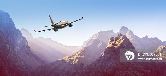 Airplane is flying over mountains in fog at sunset in summer.