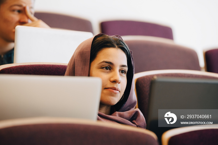 Teenage student in hijab attending lecture at high school