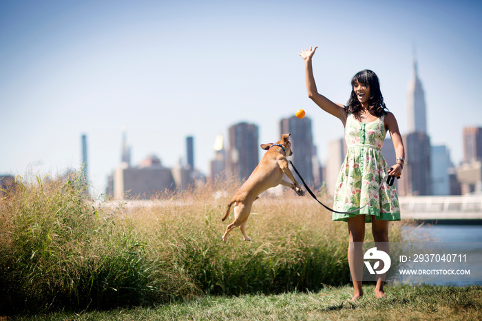 Young woman playing with dog outdoors