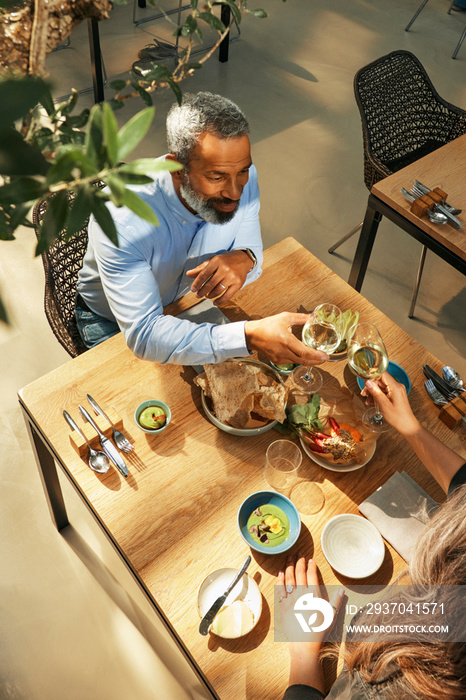 High angle mature couple toasting wine glasses in restaurant