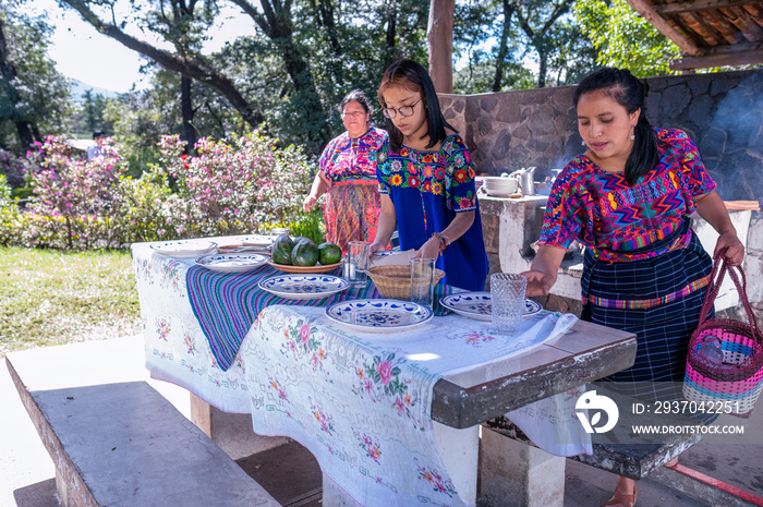 Abuela, Madre e Hija arreglan la mesa para comer. Familia Latina disfrutan el momento al aire libre.