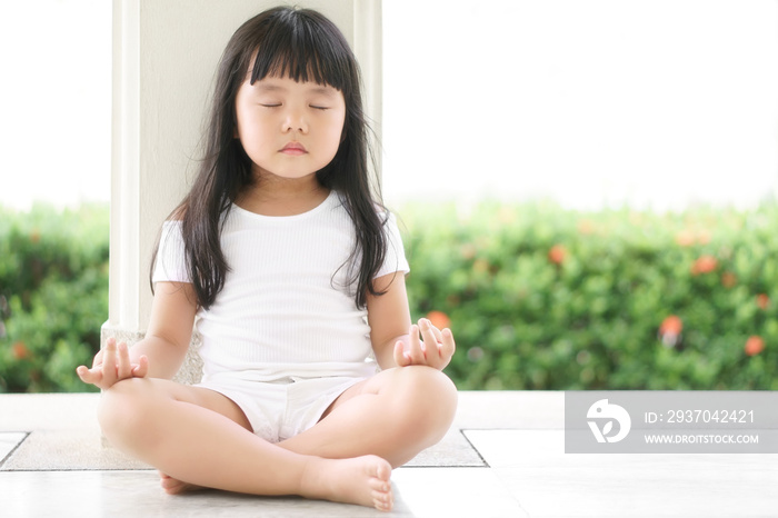 亚洲可爱的孩子或小女孩坐着进行闭眼冥想或瑜伽，寻求平静、放松或放松