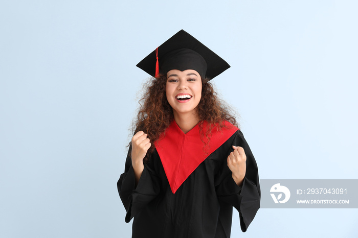 Happy African-American student in bachelor robe on color background