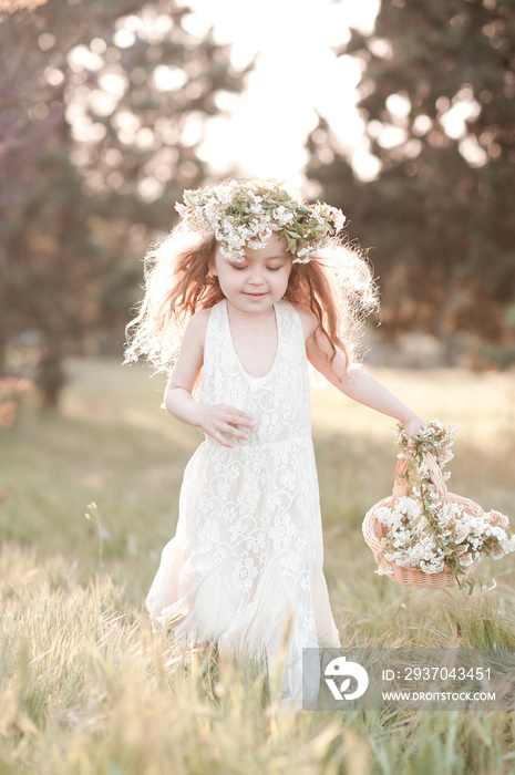 Laughing baby girl 4-5 year old running in meadow holding basket with flowers outdoors. Happiness. C