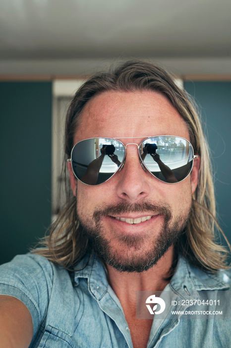 Selfie of young man wearing sunglasses with long blonde hair and