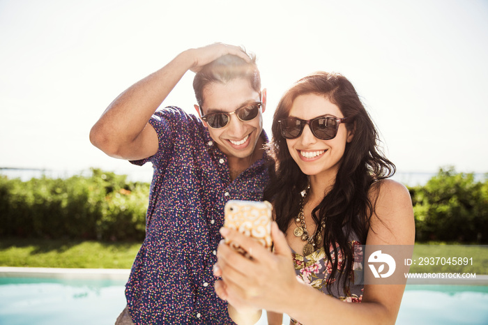 Young couple taking selfie by swimming pool