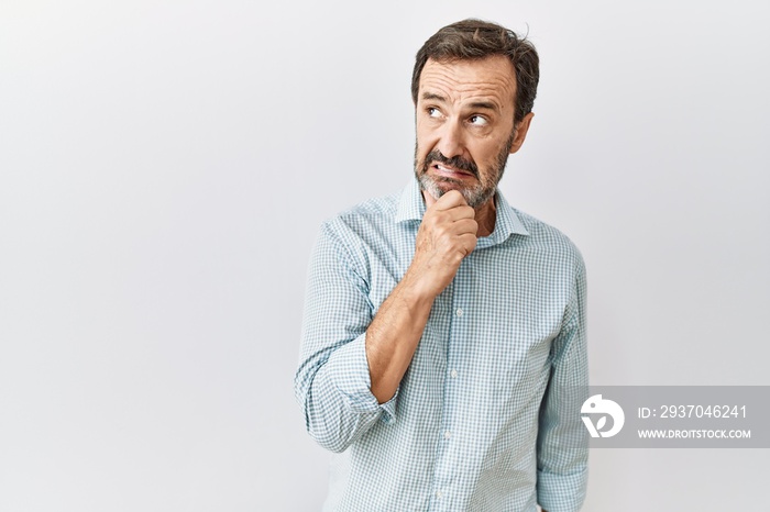 Middle age hispanic man with beard standing over isolated background thinking worried about a questi