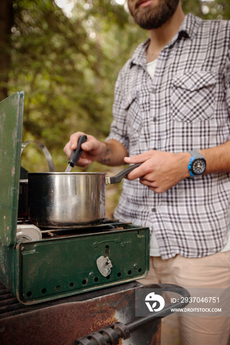 Young man cooking on camping trip