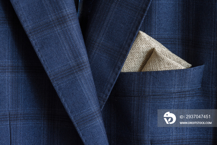Pocket square with embroidery in the breast pocket of a mans blue suit. Wedding accessories