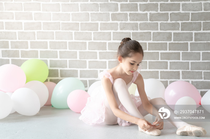 Cute beautiful young little girl ballerina dancer in pink leotard and tutu ballet dress costume sitt
