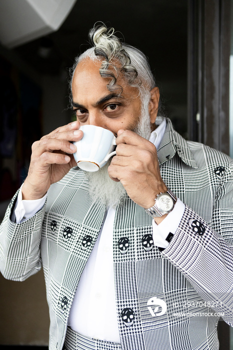 gray hair bearded man wearing suit drinking tea