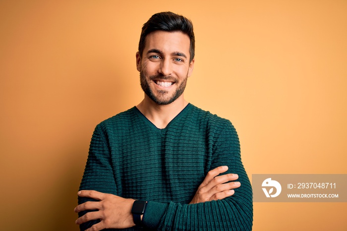 Young handsome man with beard wearing casual sweater standing over yellow background happy face smil