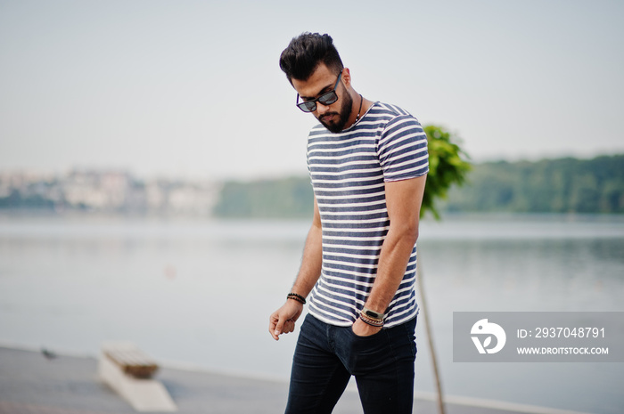 Handsome tall arabian beard man model at stripped shirt posed outdoor. Fashionable arab guy at sungl