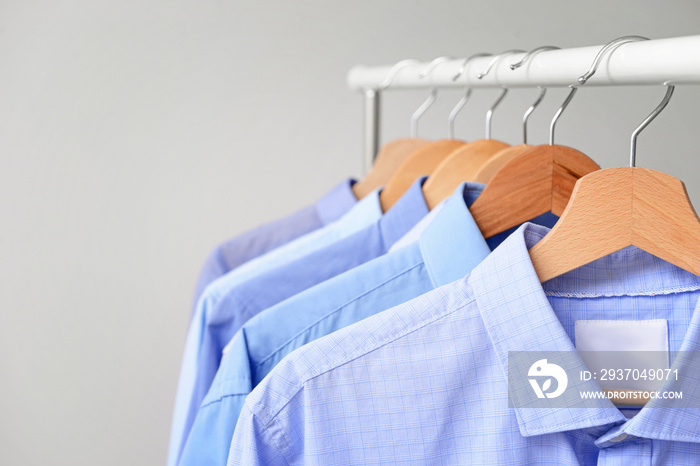 Rack with clothes after dry-cleaning on light background, closeup