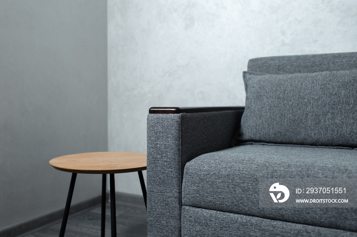 Close-up of grey sofa and small wooden table in apartment.