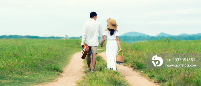 Lifestyle couple picnic sunny time. Asian young couple having fun and walking relax in the meadow an