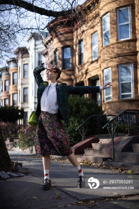 non-binary caucasian person with short hair dancing on Brooklyn sidewalk