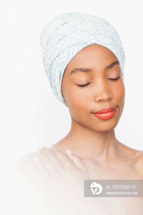 Woman wearing headwrap, hand on shoulder, eyes closed