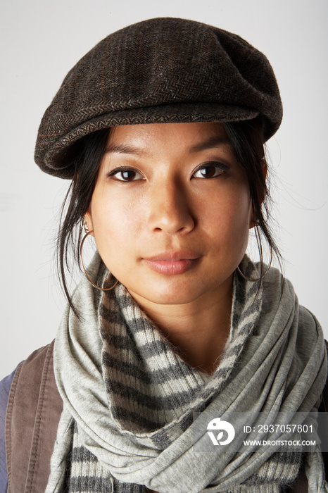 Studio portrait of mid adult woman wearing flat cap and scarf