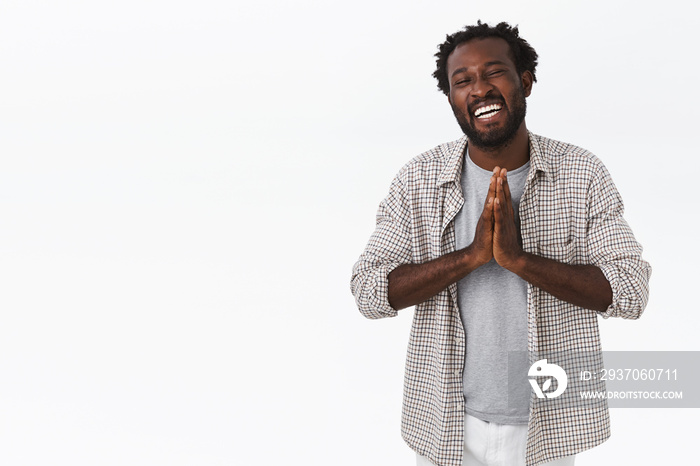 Carefree, happy and grateful kind african-american smiling man with beard, afro hairstyle, clasp han