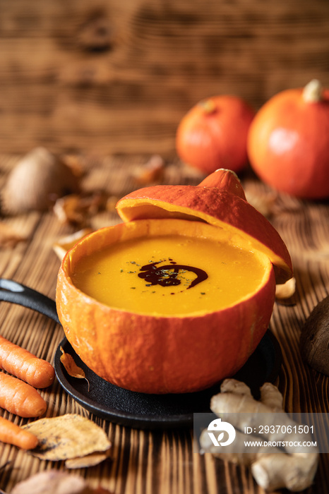 orange Suppe aus Kürbissen vom Hokkaido in einer Schale auf einem braunem Tisch aus Holz im Herbst z