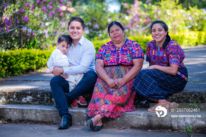 Padres jóvenes con sus hijos y abuela al aire libre sonriendo a la cámara. Retrato de una familia fe