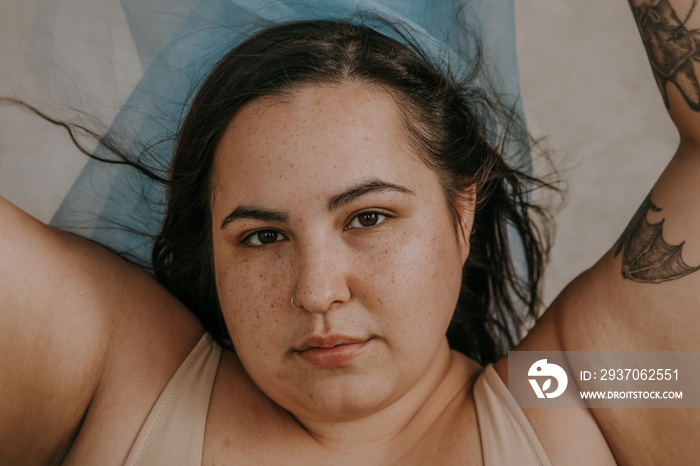 closeup plus size metis woman looking at camera holding blue fabric