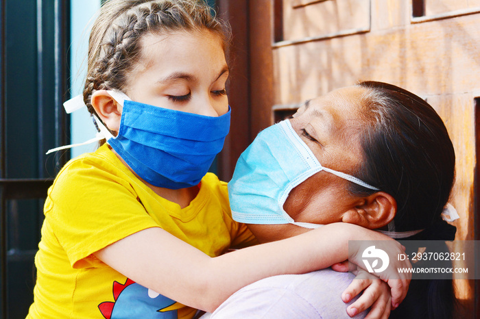 Tender portrait of native american mom with her little daughter. Both wearing masks.