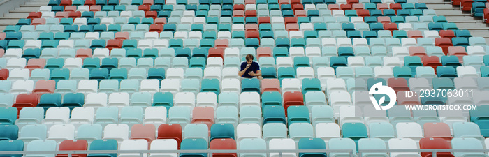 WIDE view of a lonely fan spectator attending a sports event on an empty stadium. Isolation, events 