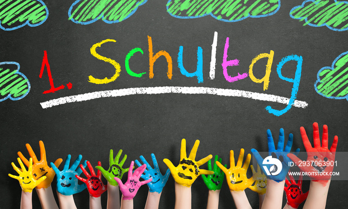 viele angemalte Kinderhände mit Smileys vor Kreidetafel mit dem Wort  1. Schultag