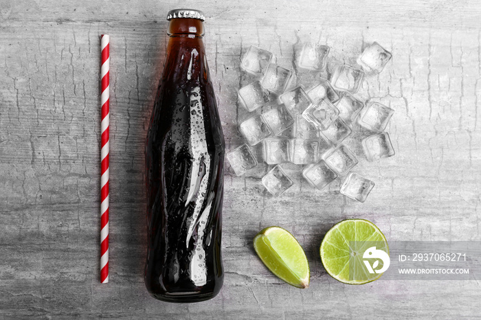 Soda bottle, ice and straw on wooden table