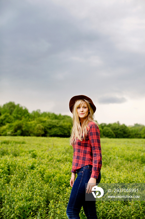 Portrait of young woman standing in meadow