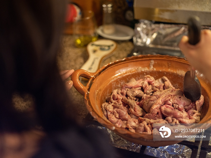 一位土著妇女在粘土锅上搅拌肉类的露肩图片